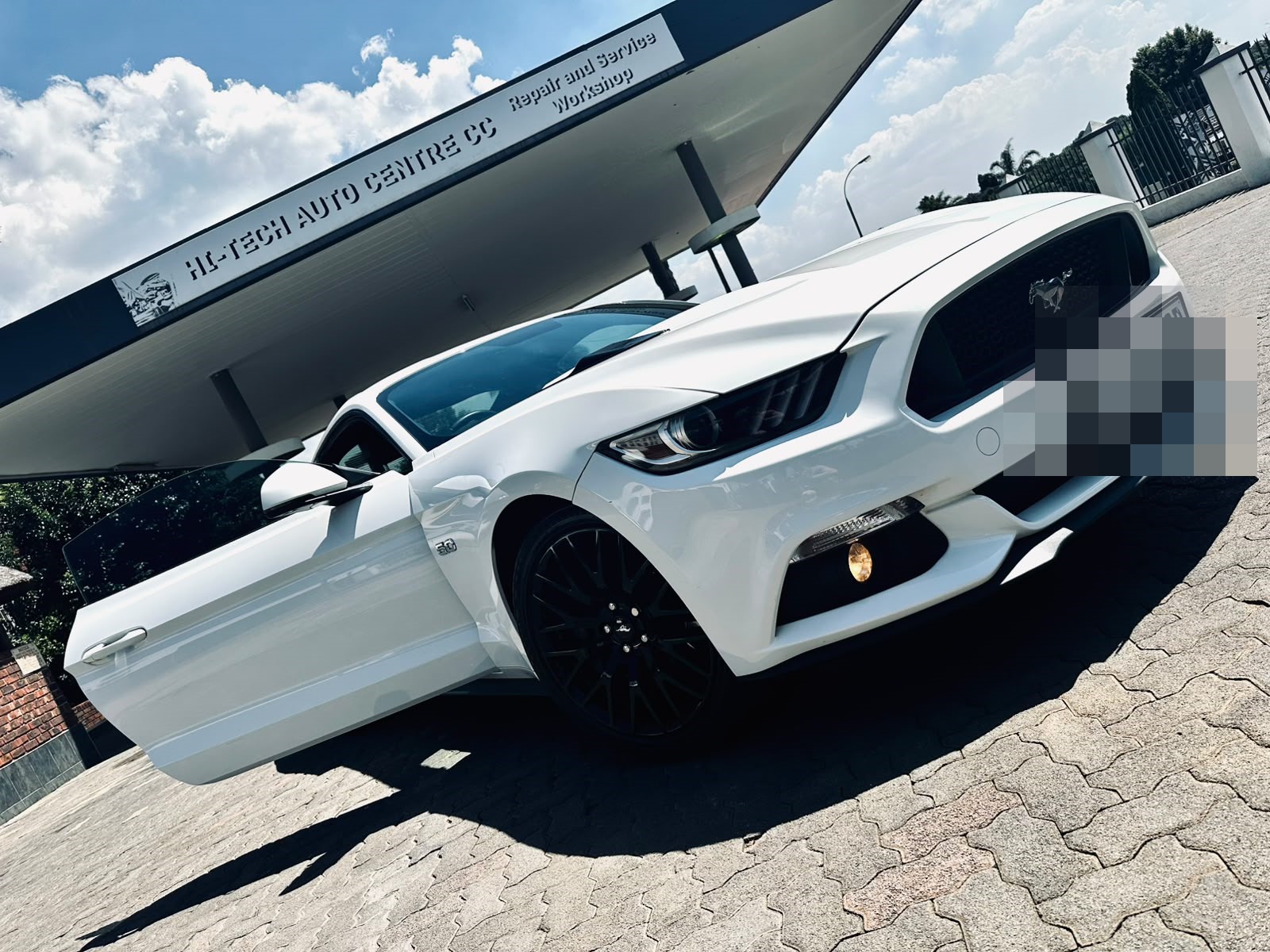 White Ford Mustang GT under the Hi-Tech Auto Centre forecourt signage in Norkem Park